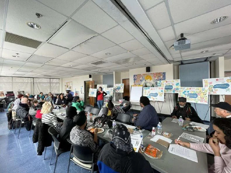 A group of people sit at tables and look at poster boards.